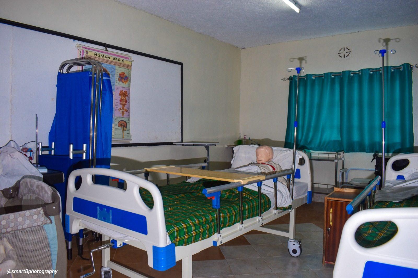The nursing skills lab: a hospital bed with a training manikin, drip stands and an anatomy chart